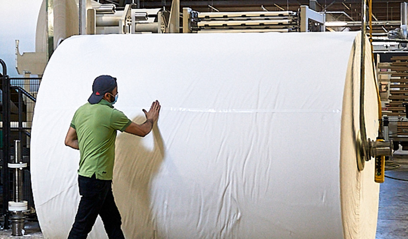 Factory worker assisting with production of tissue paper