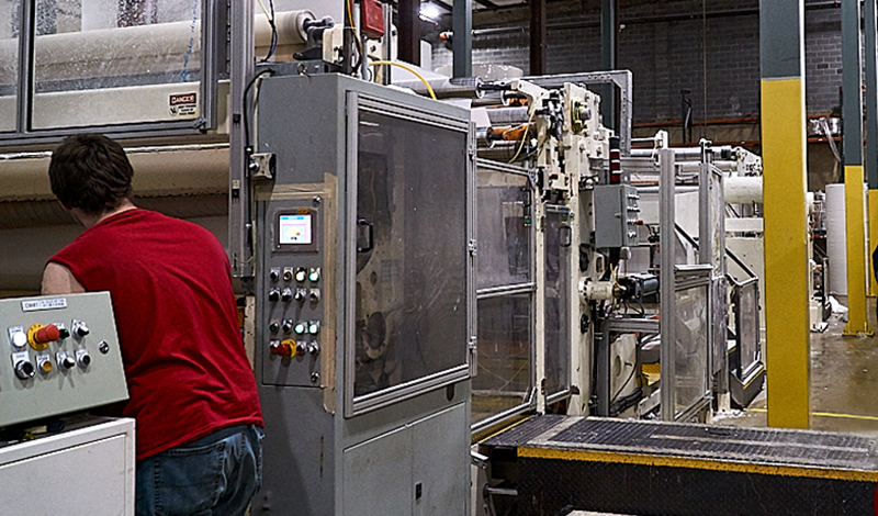 Factory worker assisting with production by using machinery